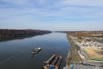 Looking north at a barge, railroads on either side of the river.